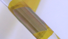 A yellow patch of microelectronics wrapped around a thin glass tube