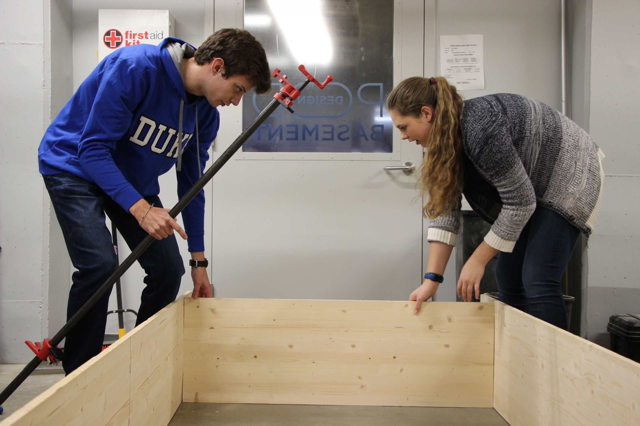 Students begin assembling a bookshelf to be placed in the shipping container