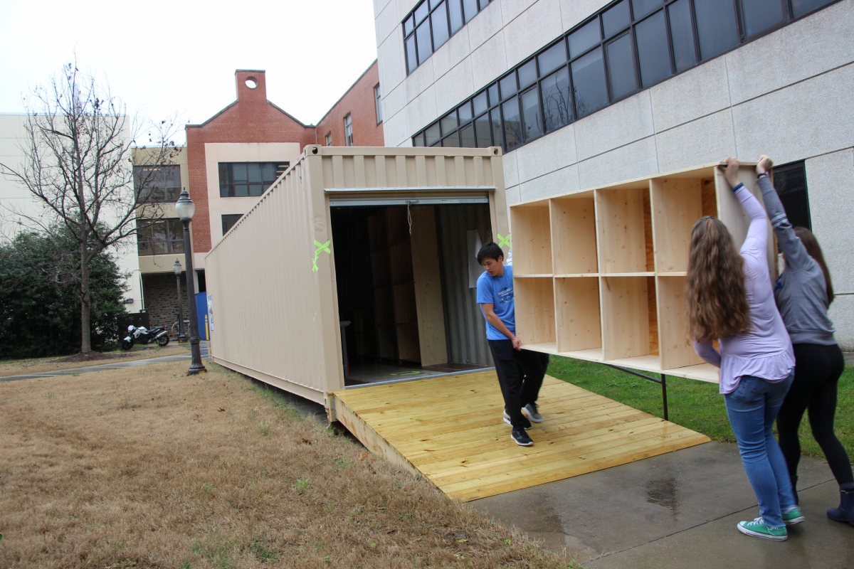The team brings the bookshelf to the storage container