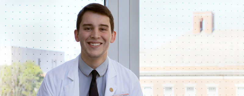 Duke MD-MEng student Joshua D'Arcy in a white coat 