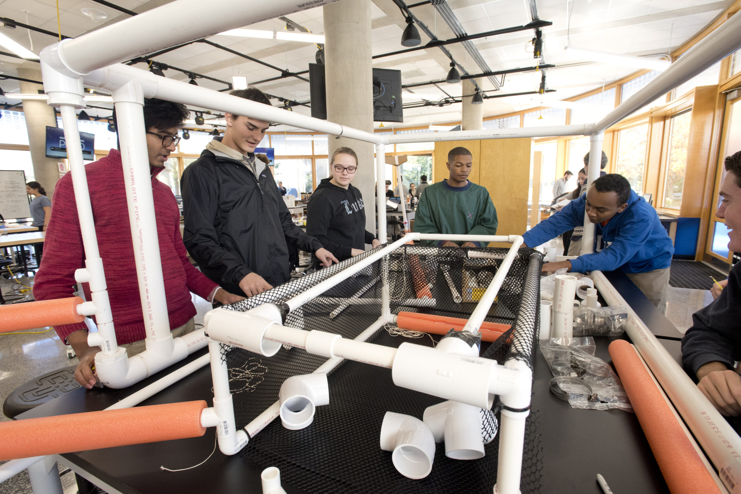 Engineering students build a large cube using PVC pipes and fittings