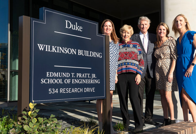 Wilkinson family with sign outside building