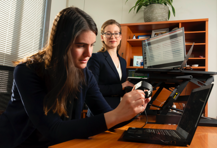 Ph.D. student Brinnae Bent prepares to download information from a wearable health monitoring device while assistant professor Jessilyn Dunn looks on. (Les Todd)