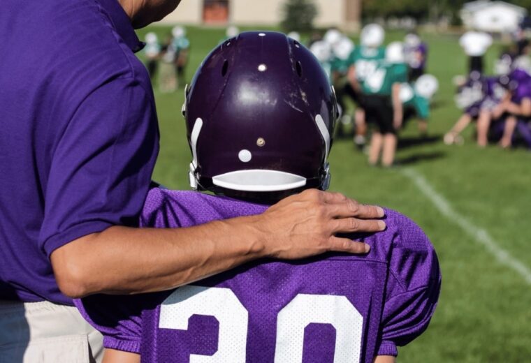 American football coach and young player in uniform