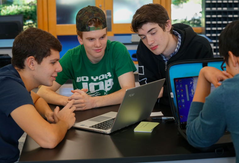 three engineering students look at a laptop computer