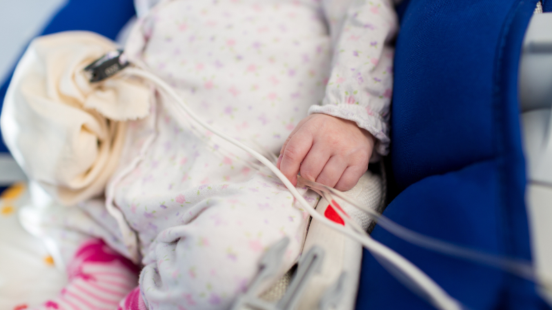 The torso of a child with a bag on its stomach and a medical line feeding into it