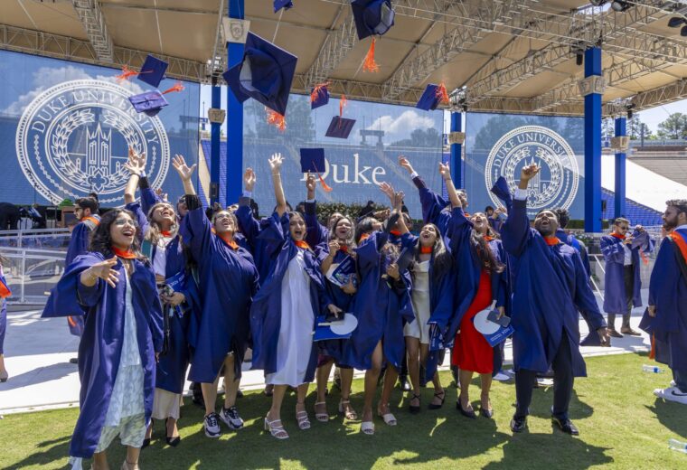 Pratt School of Engineering graduates toss their caps in the air at Wallace Wade Stadium