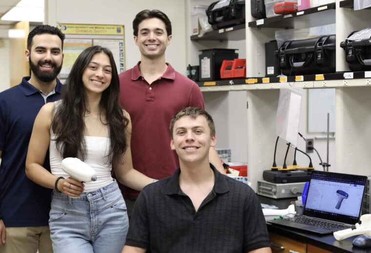 Four students pose in a lab with a white prototype of a their low-cost tympanometer device